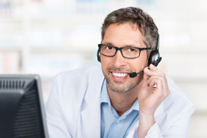 Smiling Pharmacist Wearing Headset At Counter