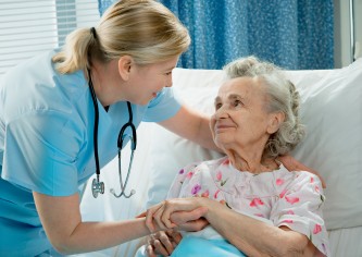 Nurse cares for a elderly woman lying in bed