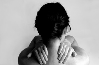 Nude woman with back pain on a gray background