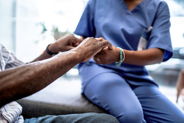 Enfermera sosteniendo las manos de un paciente | iStock