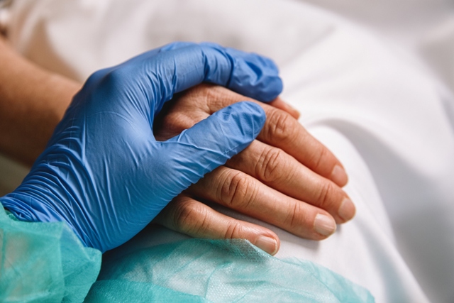 Profesional sanitario dándole la mano al paciente | iStock